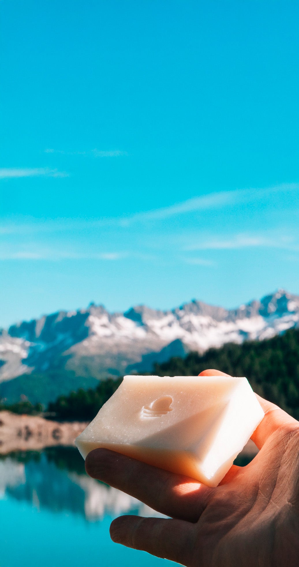 Handgemachte Tallow-Seife von Helvera vor Schweizer Alpen und Bergsee – reine Naturseife aus 100 % Rindertalg, im Hochformat festgehalten